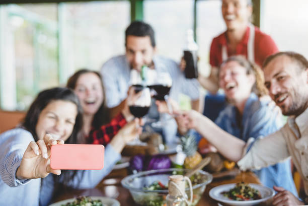 groupe d’amis heureux prenant selfie utilisant l’appareil-photo mobile de téléphone intelligent-jeunes gens de millénaire ayant l’amusement au temps de dîner-amitié, nourriture et boisson, technologie et concept de mode de vie de jeunesse - restaurant dinner dining gourmet photos et images de collection