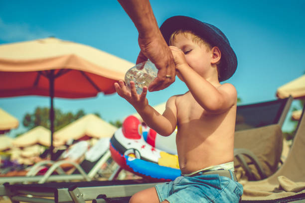 istock Father helping his son to drink water on the beach 1147098921