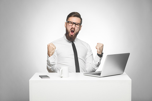 Angry stressed businessman yelling at his computer, overwork and computer problems concept