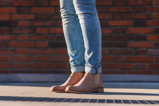 istock Female legs wearing jeans and leather boot standing next to brick wall. 1147103467