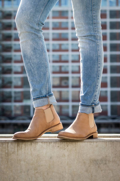 도시에서 청바지와 가죽 신발을 입고 세련 된 슬림 다리. 배경으로 현대 건축. - wall women leather street 뉴스 사진 이미지
