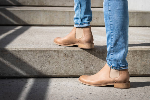 istock Legs in denim pants and leather boot on staircase. 1147103574