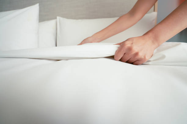 Female Hand set up white bed sheet in room hotel stock photo