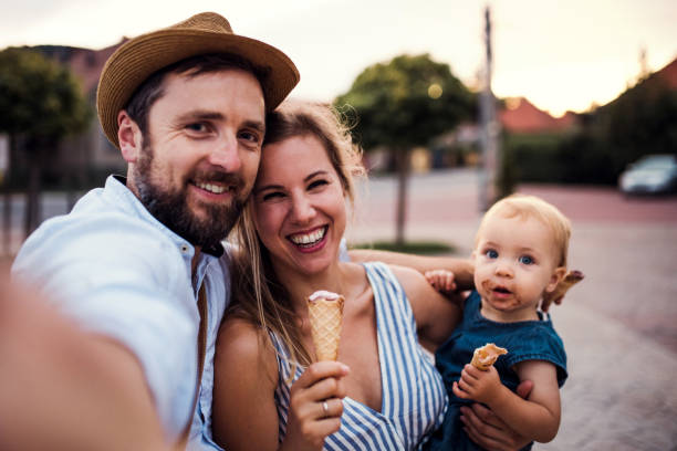 parents et petite fille d’enfant en bas âge avec la crème glacée à l’extérieur en été, prenant le selfie. - ice cream people food recreational pursuit photos et images de collection