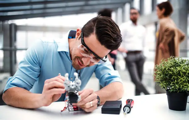 Photo of A young businessman or scientist with robotic hand standing in office, working.