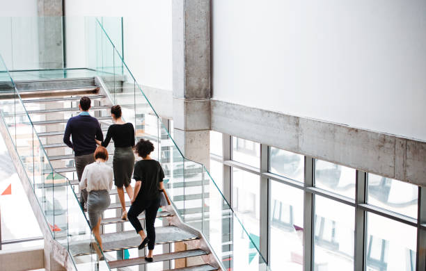 vue arrière du groupe de jeunes gens d’affaires marchant dans les escaliers. - marches et escaliers photos et images de collection