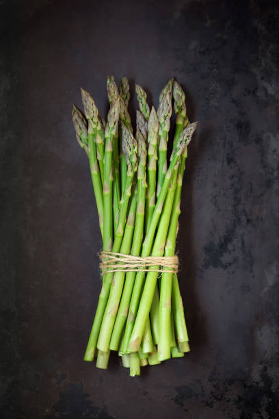 istock Fresh asparagus in a bunch against dark background 1147109885