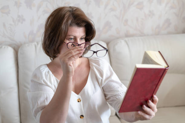 istock Woman with impaired vision reading a book through two glasses 1147110178