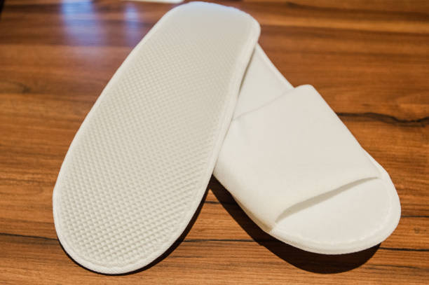 hotel flip flop, Hotel Guest Room Supplies A pair of white disposable slippers with soft foam texture for indoor shoe isolated on dark wood floor stock photo