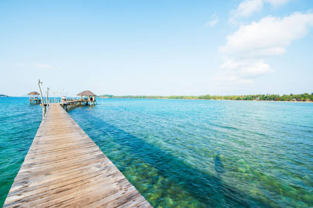 istock Empty wood bridge extending into the clear blue sea. 1147113377
