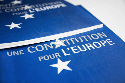 Close-up on French European Union constitution documents blue colored, selective focus on title on first page of the brochure with white color stars, placed on white table in studio.