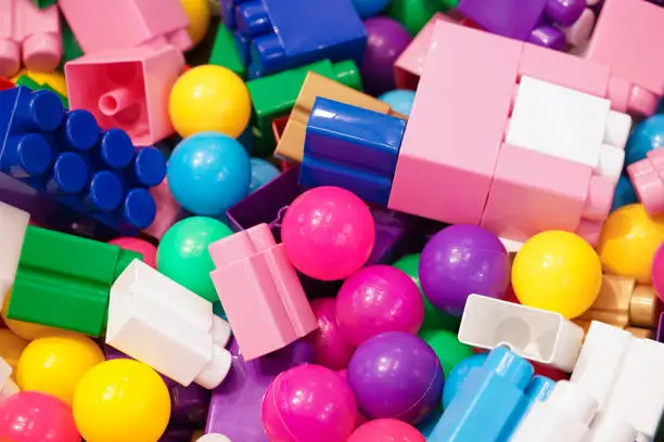 Piles of toys. A lot of colorful toys including balls and plastic construction toys or building blocks, top view. Toy for children to develop creativity. Soft focus on the pink ball in the middle.