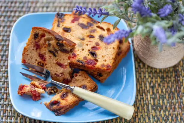 Muffins with raisins and bouquet of lavender on a rustic wooden table. Fruitcake or slices cupcake on a blue plate. Dessert. Soft focus. Blurry background. Copy space. Close-up and top view.