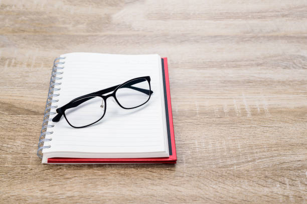 istock Concept Education or business  : Open diary  or note book with black glasses on wooden table. 1147125139