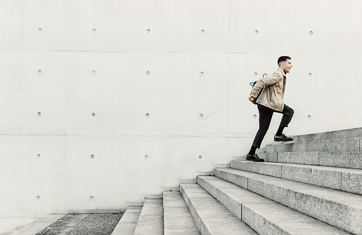 Young man running up steps in urban setting