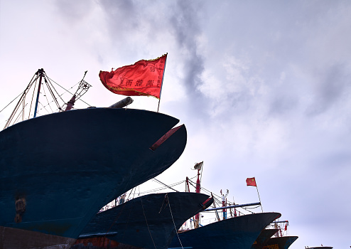A fleet of Chinese fishing boats is seen against the blue sky，The bow of a red flag, the flag printed: full of return.