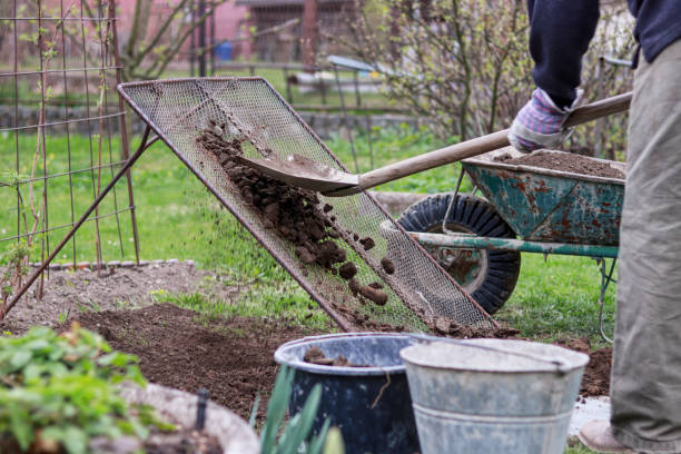 adult man works on garden. man shovel soil through homemade screen for sorting on stones and clay. homemade device for sifting clay. shovel, wheel. landscaping work. hard working man. manual work. - sifting imagens e fotografias de stock