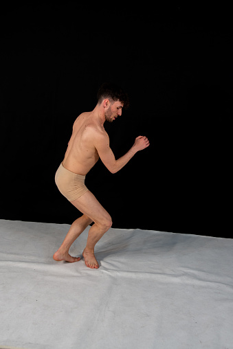 The attractive young man shows modern dance poses, on a black background.