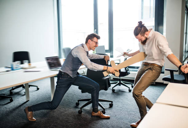istock Two young businessmen with swords in an office, having fun. A competition concept. 1147137212