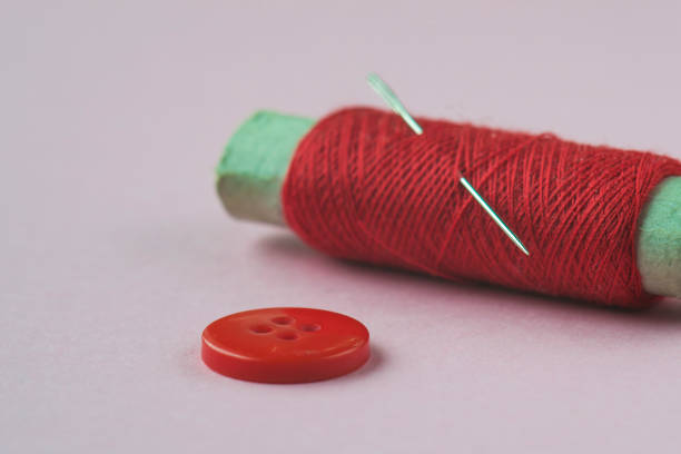 istock Red button, reel of red thread and needle close-up. 1147139360