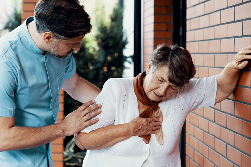 Enfermera masculina que ayuda a la anciana enferma con dolor torácico photo