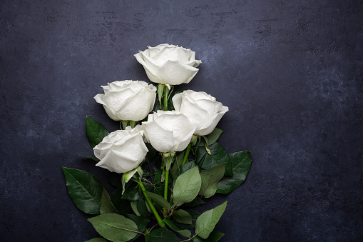 White rose flowers bouquet on black stone background Romantic greeting card Copy space Flat lay