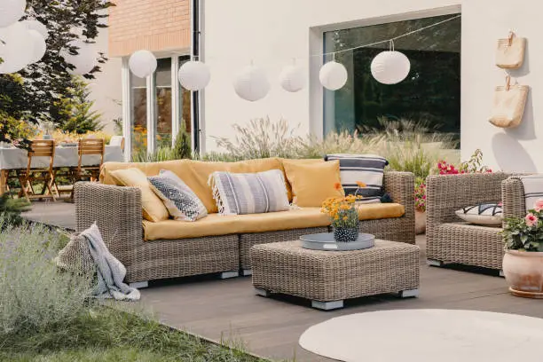 Photo of Real photo of a rattan garden furniture set with lamps and table in the background