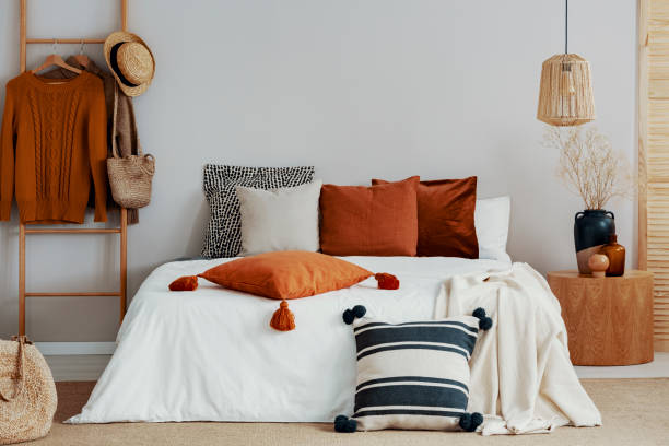 almohadas coloridas en la cama blanca de la habitación con clase con mesita de noche de madera redonda y escalera - decor indoors pillow bedroom fotografías e imágenes de stock