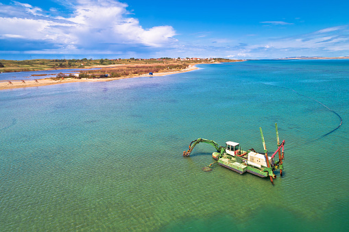 Dredger boat excavating sand for beach in shallow water near town of Nin, Dalmatia region of Croatia