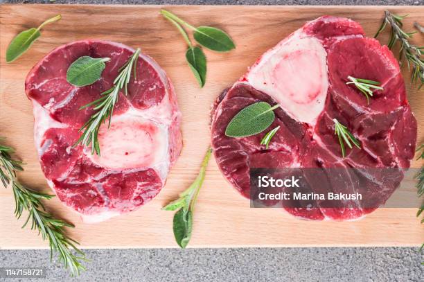 Sliced Meat On A Wooden Board With Herbs And Spices Raw Meat On The Bone Closeup Gray Background Stock Photo - Download Image Now