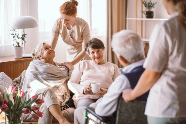 Young caregiver comforting elderly woman in nursing home Young caregiver comforting elderly woman in nursing home civilian stock pictures, royalty-free photos & images