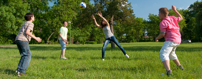 Teenagers playing with the ball in the nature on a sunny spring day.