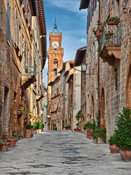 Pienza, Siena, Tuscany, Italy: the picturesque main street of the city with the ancient buildings and the clock tower on background