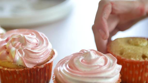 istock Decorating cup-cake with cream. Using cooking bag, confectioner making multicolor cupcakes for party. Shot of woman's hands putting butter cream on the tasty cakes, home bakery concept 1147178290