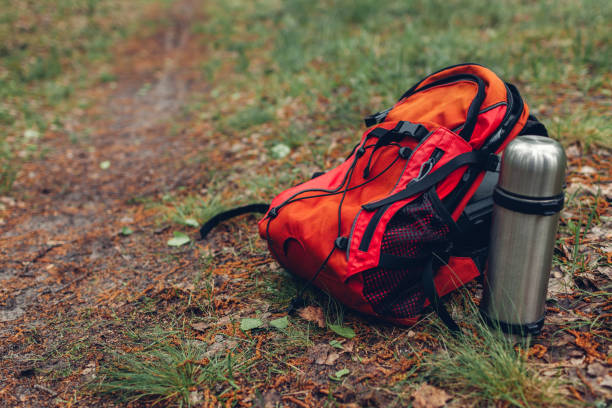 istock Tourist's backpack, thermos with tea in spring forest. Traveling and sport 1147182254