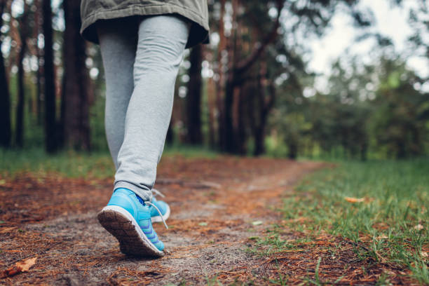 woman tourist walking in spring forest. close up of shoes. traveling and tourism concept - shoe tying adult jogging imagens e fotografias de stock