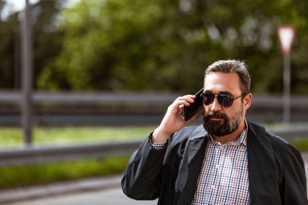 istock Handsome mature creative freelance businessman talking on the mobile phone and smiling while walking outdoor urban area in the street in Staying connected and entrepreneur creative business concept. 1147189111