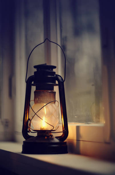 an old kerosene lamp stands on a white windowsill - oil lantern imagens e fotografias de stock