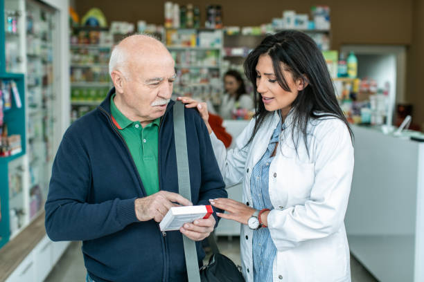 Female pharmacist giving medications to senior customer stock photo