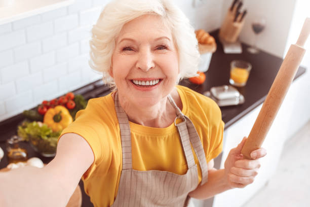 istock Old housekeeper making selfie toothy smile, holding a rolling pin 1147195705