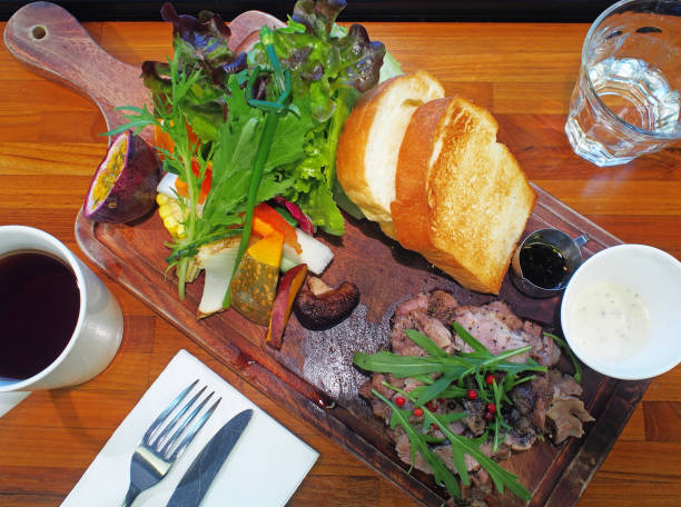 Baby back ribs with vegetable salad, bread and creamy salad dressing on wooden board
