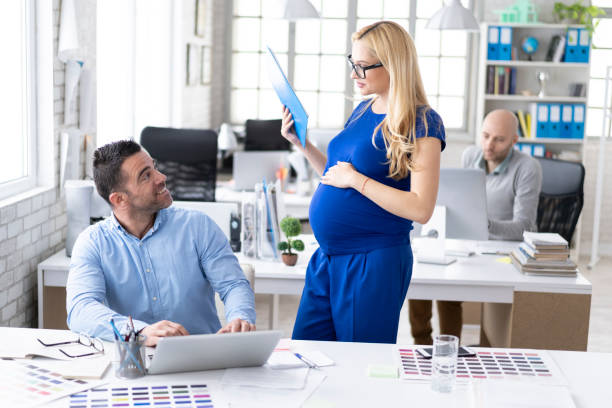 istock Male designer discussing ideas with pregnant assistant at workplace 1147201055