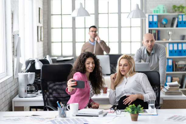 istock Smiling coworkers taking selfie at workplace 1147201147