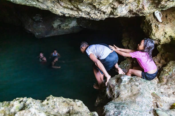les adolescents polynésiens locaux se baignant dans la grotte de veimumuni, tandis qu’une petite fille pousse un garçon à la piscine. flou de mouvement. près de neiafu, vava’u, polynésie, océanie, océan pacifique sud - vavau islands photos et images de collection