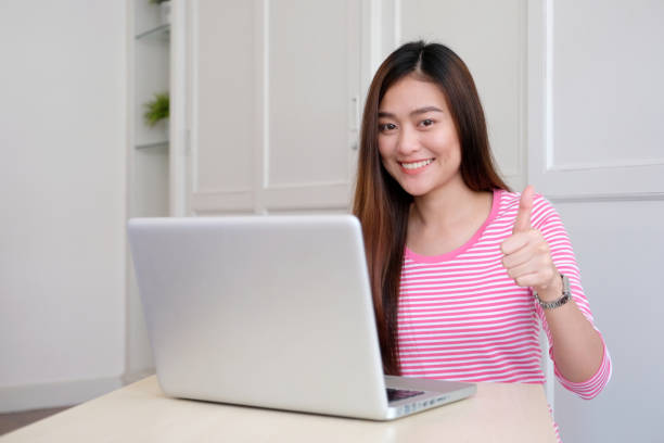 istock Young asian woman thumb up while working with laptop computer, people working with positive expression 1147224782