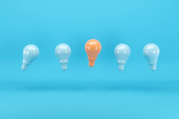 istock Outstanding light orange light bulb among blue light bulbs floating on blue background. Minimal conceptual idea concept. 1147227071