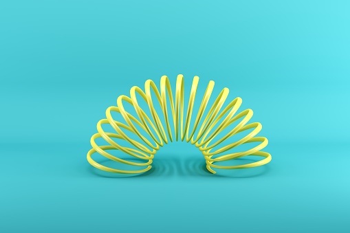Amarillo Slinky aislado sobre fondo azul. Concepto de idea conceptual minimalista. photo