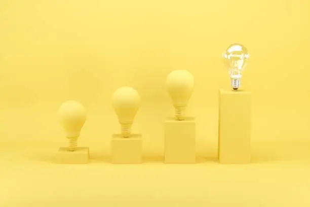 Photo of Outstanding light bulb among light bulbs painted in yellow on bar chart on yellow background. Minimal conceptual idea concept.