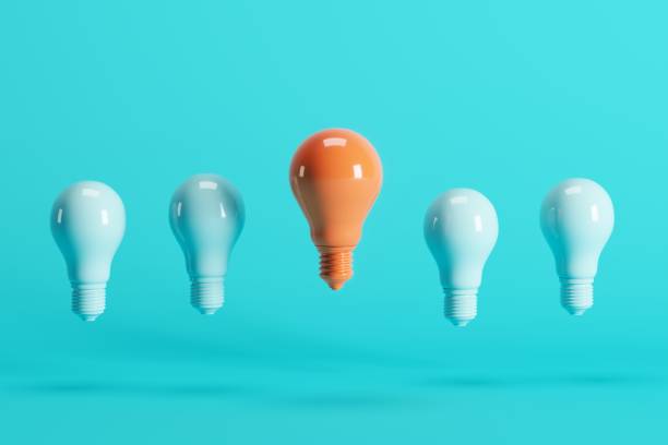 istock Outstanding orange light bulb among light blue light bulbs floating on blue background. Minimal conceptual idea concept. 1147227092