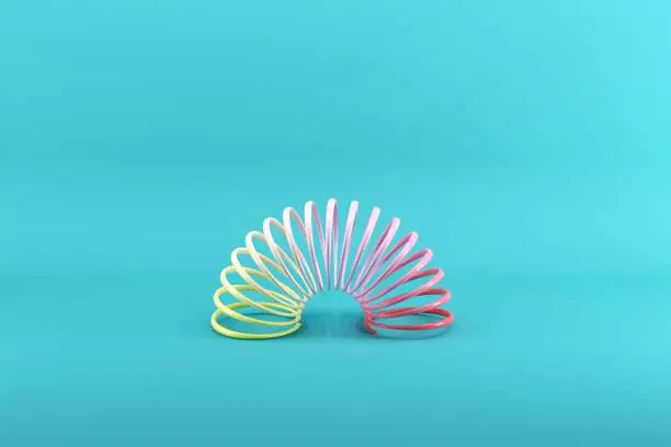Photo of Colorful slinky on blue background. Minimal conceptual idea concept.